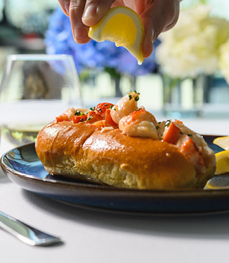 New England hot lobster roll with lemon being squeezed over the top of it, served on American Cruise Lines.
