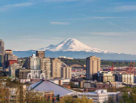 A Seattle cityscape featuring the Seattle Space Needle and Mount Denali in the distance.