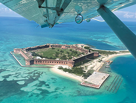 An aerial view of Dry Tortugas National Park, a hexagonal island enclosed by brick walls in the middle of the bright blue water from "Seaplane Adventure", an American Cruise Lines excursion.