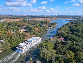 An aerial view of American Liberty navigating through Elliot Cut, one of the small waterways within the Intracoastal Waterway near Charleston, where both sides of the water are covered with dense forests.