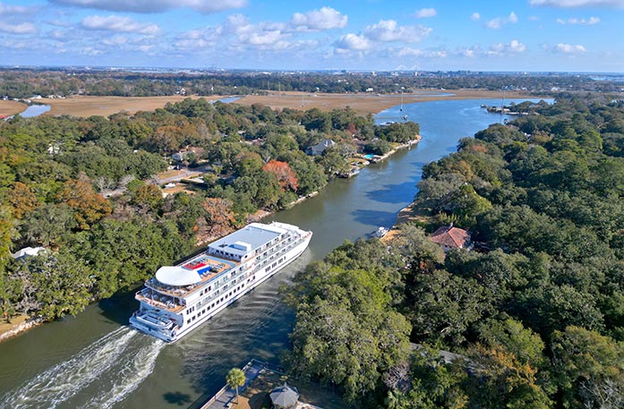 An aerial view of American Liberty navigating through Elliot Cut, one of the small waterways within the Intracoastal Waterway near Charleston, where both sides of the water are covered with dense forests.