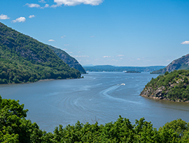 An Aerial view of the Hudson River with cliffs on each side of the water, and small mountains in the distance.