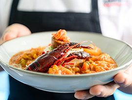 A close up view of a person holding a bowl of Crawfish Etouffe served on American Cruise Lines.