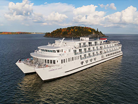 American Eagle Coastal Cat sailing along the Maine coast, where there is a small island in the middle of the water.