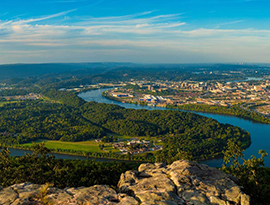 Aerial view of the winding Mississippi River with sights of a large city in the distance.