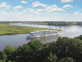 American Riverboat gliding smoothly along the Mississippi River, surrounded by lush greenery and scenic views.