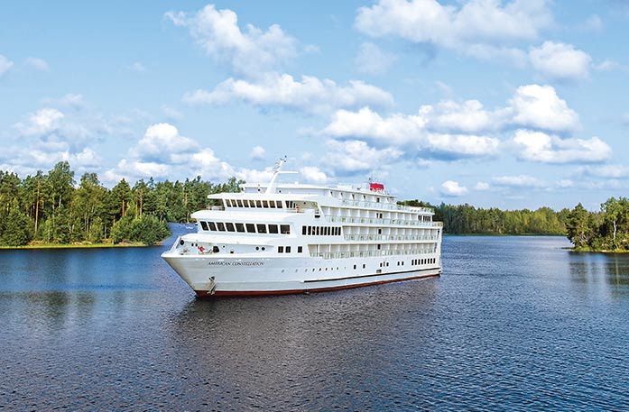 A Constellation Class Coastal Cruise Ship sailing along a scenic tree lined waterway.