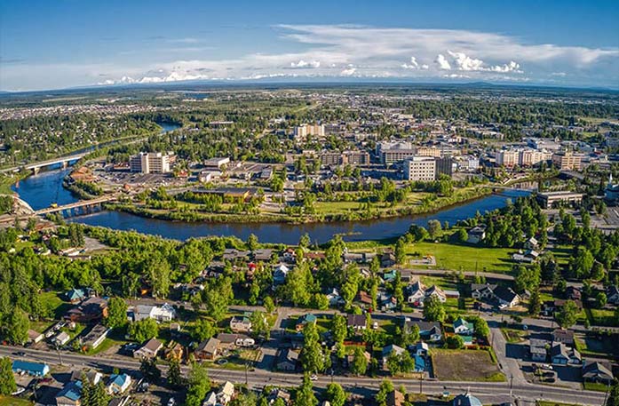 An aerial view of the buildings and greenery of Fairbanks, with the Chena River winding through the center.