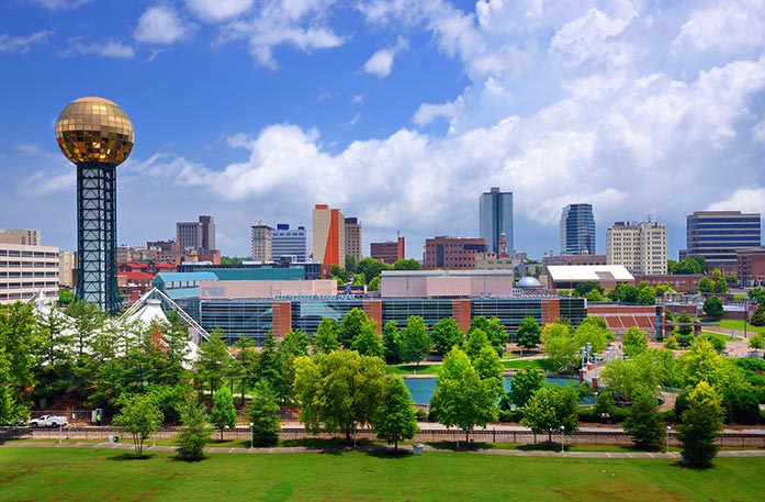 Skyline of Knoxville, a city with modern buildings, including the Knoxville Convention Center which features the Sunsphere, a tower with a gold ball on top.