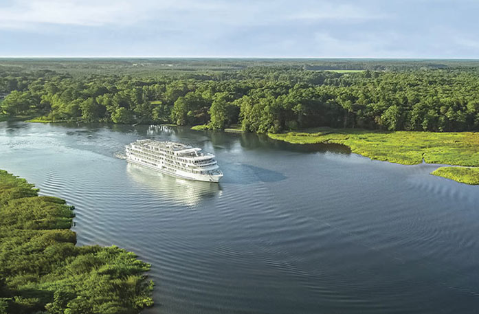 An American riverboat gliding along the Ohio River surrounded by green landscapes.