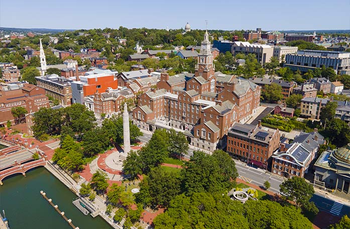 An aerial view of the town of Providence, with the large brick building of State Law Library in the center and WWI memorial monument in front of it surrounded by trees in Memorial Park.