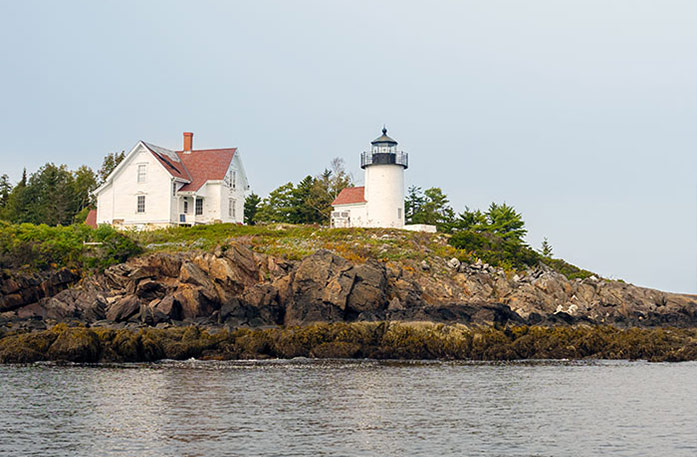 Curtis Island Lighthouse, a small white lighthouse beside a small white building with a red roof on top of a cliff along the Maine coast in Rockland.