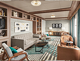 The Storyteller Lounge, a common area on American Encore, with a tan couch against the wall with two arm chairs facing the windows directly across, and two sets of leather lounge chairs beneath the windows. On the wall above the couch, there are several shelves with miscellaneous decor. 