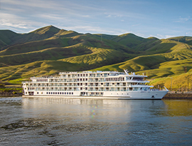 American Jazz, an American Riverboat small cruise ship docked along the Columbia River in Lewiston, beside the vast hills and valleys of the area.